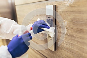 Staff using disinfectant from the bottle spraying an elevator push button control panel.