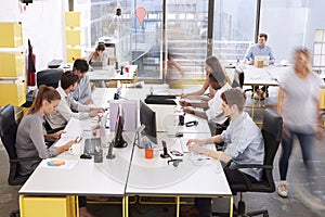 Staff walking through a busy open plan office, side view