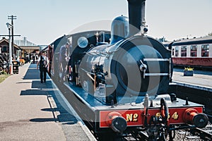 Staff walking on platform next to The Poppy Line steam train, Sheringham, Norfolk, UK