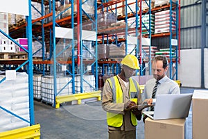 Staffs discussing over clipboard in warehouse