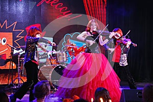 On stage, the expressive red-haired violinist Maria Bessonova sons twins. violin trio two generations of red fiery musicians.