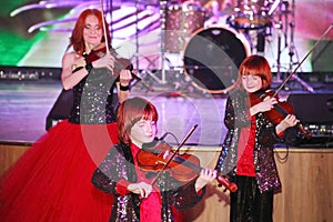 On stage, the expressive red-haired violinist Maria Bessonova sons twins. violin trio two generations of red fiery musicians.