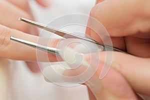 Stage of manicure: nail shaping by tweezers