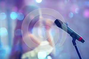 Stage microphone against the background of a blurred singer in spots of blue bokeh. performance or recital