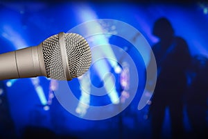 Stage microphone with a guitarist on the back blurry background photo