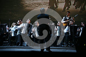 On stage, the musicians and soloists of Orchestra of accordionists (harmonic orchestra) under the baton of conductor.