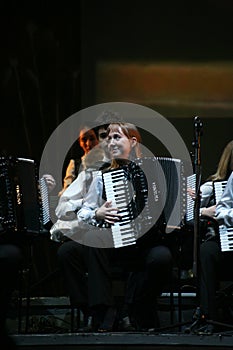 On stage, the musicians and soloists of Orchestra of accordionists (harmonic orchestra) under the baton of conductor.