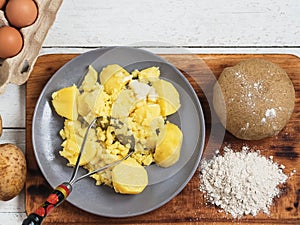 The stage of preparation of the national dish is Karelian pies. Boiled potatoes on a plate, next to flour and rye dough.