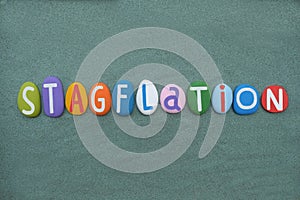 Stagflation, economic term composed with multi colored stone letters over green sand