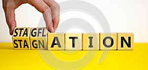 Stagflation or stagnation symbol. Businessman turns cubes, changes the word stagnation to stagflation. Beautiful yellow table