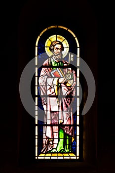 Stained glass inside a Christian church in Europe depicting Church Saint figure. Close up shot, no people, low key