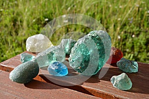 Stained glass from old glassworks smoothed and rounded in a mountain river collected by children beautifully stand out in the sun