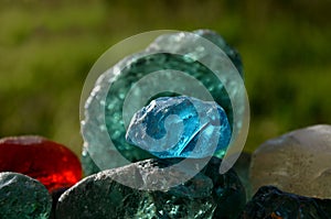 Stained glass from old glassworks smoothed and rounded in a mountain river collected by children beautifully stand out in the sun