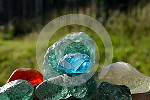 Stained glass from old glassworks smoothed and rounded in a mountain river collected by children beautifully stand out in the sun