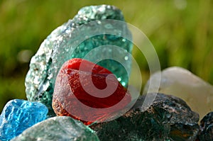 Stained glass from old glassworks smoothed and rounded in a mountain river collected by children beautifully stand out in the sun