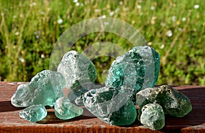 Stained glass from old glassworks smoothed and rounded in a mountain river collected by children beautifully stand out in the sun