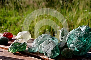 Stained glass from old glassworks smoothed and rounded in a mountain river collected by children beautifully stand out in the sun