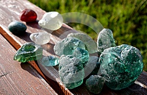 Stained glass from old glassworks smoothed and rounded in a mountain river collected by children beautifully stand out in the sun