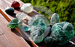 Stained glass from old glassworks smoothed and rounded in a mountain river collected by children beautifully stand out in the sun