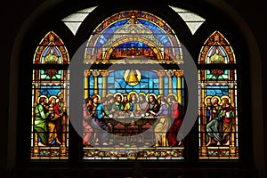 stained glass window depicting the last supper, with a view of individual pieces of mosaic art adorning the background