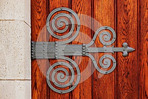 stained red brown oak wood gate leaf with new forged wrought iron mounting or embossing hinge