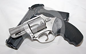 A stainless 357 magnum revolver on top of a black 40 caliber semiautomatic pistol