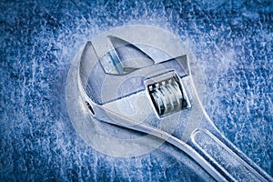 Stainless adjustable spanner on scratched metallic background co