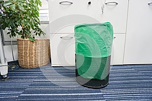 Stainless bin with green plastic bag in office