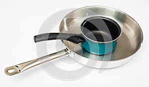 Stainless frying pan and blue non-stick saucepan on white