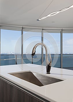 Stainless kitchen faucet with white counter tops and a view