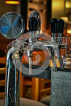 Stainless steel beer faucets with black handles.