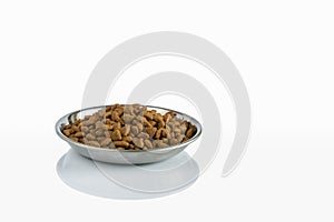 Stainless steel cat feeding plate filled with dry food isolated on white background with reflection