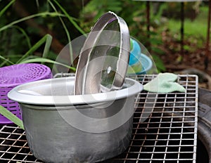 Stainless steel cooking pots are placed in the sink on the patio.