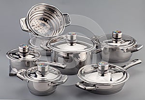 Stainless steel cookware, pots and pans on gray background. Kitchenware set utensils