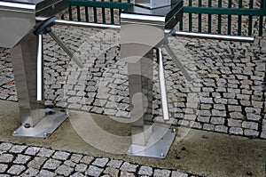 Stainless steel entrance turnstiles for tickets. placed outside on cobblestone pavement. it is an automatic entry to the tickets l