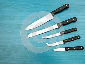 Stainless steel kitchen knives set on stained wood surface