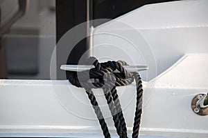 stainless steel mooring cleat aboard a fiberglass boat with tethered rope