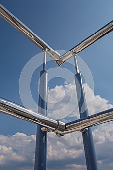 Stainless steel railing stairs from the outside of the building on a background of blue sky and beautiful clouds. Pipes, hinges,