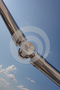 Stainless steel railing stairs from the outside of the building on a background of blue sky and beautiful clouds. Pipes, hinges,