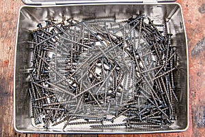 Stainless steel screws in box. Pile of wood screws top view. Large number of self-tapping.