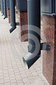 Stainless steel shiny downpipe at the corner of the house, close up