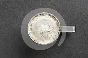 Stainless steel sifter full of flour on grey background