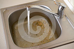 Stainless steel sink plug hole close up full of water and particles of food photo