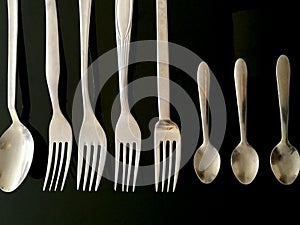 Stainless steel spoons and forks in a row