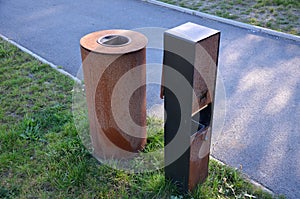 Stainless steel with a surface rusty oxidized layer of rust. On the square in the park, these metal trash cans have bags of dog ex