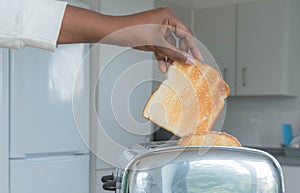 Stainless steel toaster toaster with fresh toasted bread for breakfast. Hands of African American