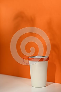 A stainless steel travel mug over orange background. Tumbler beverage container and Eco friendly lifestyle