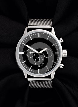 Stainless steel watch with black face on black background