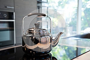 Stainless Water Crow or Vintage Kettle tea pot on electronic stove in modern Kitchen room