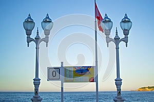 Stair 0 Escalera 0 with Gijon`s flag and two streetlights in San Lorenzo beach, Gijon, Asturias Spain